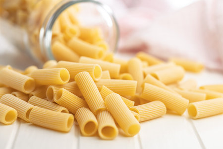 Uncooked rigatoni pasta on a white table.