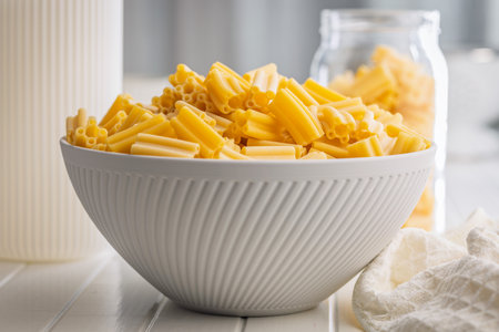 Uncooked italian pasta in a bowl on a white table.の写真素材