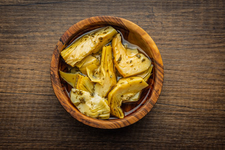 Pickled artichoke in bowl on a wooden table. Top view.の写真素材