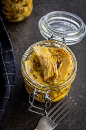 Pickled artichoke in jar on a black table.の写真素材