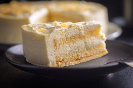 Sweet creamy cake on a plate on a black table.の写真素材