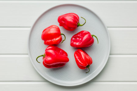 Red chili pepper habanero on plate on a white table. Top view.