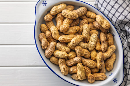 Peanuts in shell. Groundnuts in a bowl on a white table. Top view.