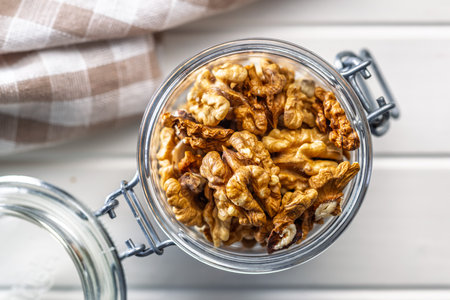 Peeled walnut kernels in a jar on a white table. Top view.の写真素材