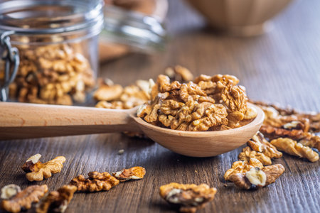 Peeled walnut kernels on a wooden spoon on a wooden table.