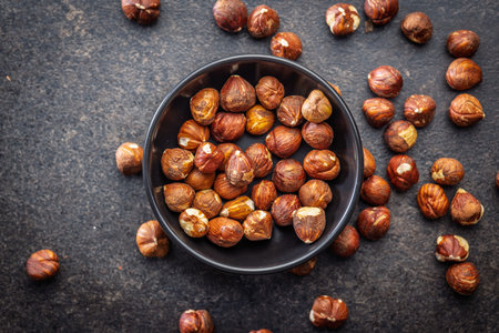 Peeled hazelnut kernels in a bowl on a black table. Top view.の写真素材