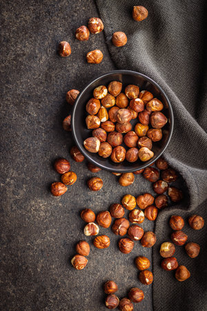 Peeled hazelnut kernels in a bowl on a black surface. Top view.の写真素材