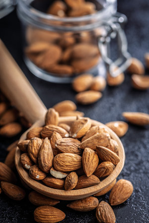Almond kernel nuts on wooden spoon on a black table.の写真素材
