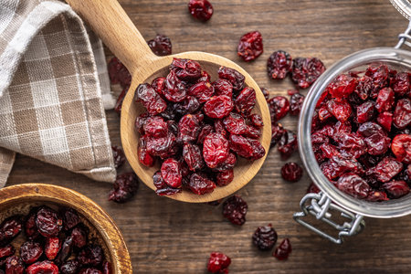 Tasty dried cranberries on a wooden spoon on a wooden table. Top view.の写真素材