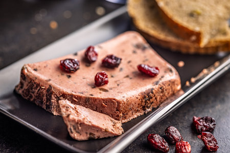 Liver pate with cranberries on a black plate.