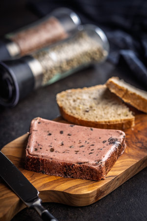 Liver pate with cranberries on a wooden cutting board.