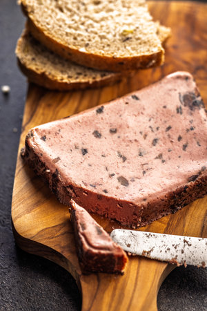 Liver pate with cranberries on a wooden cutting board.