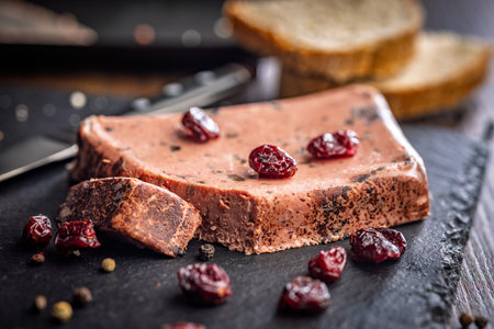 Liver pate with cranberries on a stone cutting board.