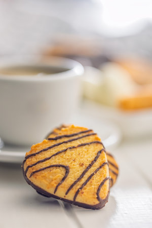 Heart shaped cookie and coffee cup on a white table.の写真素材