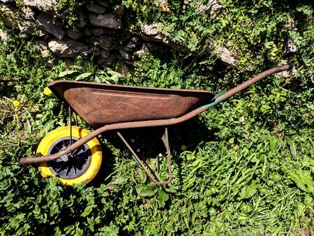 old wheelbarrow with yellow wheel on the grassの写真素材