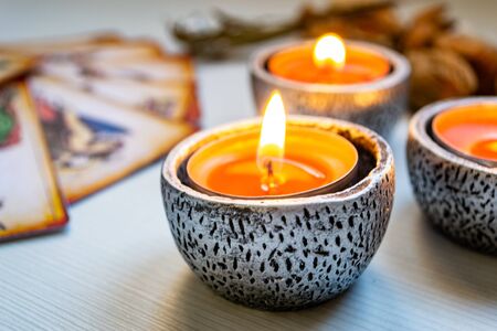 Tarot cards with red candles on a white wooden table background. Concept of divinationの写真素材