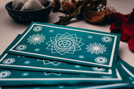 Green tarot cards with different mystical objects on white wood. Spiritual concept