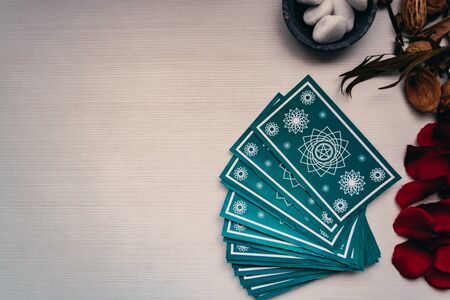 Green tarot cards with different mystical objects on white wood. Space for texts