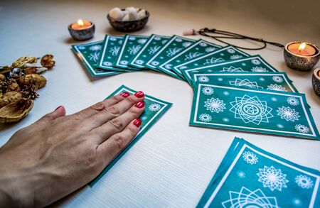 fortune teller with green tarot cards on a white wooden table background. Concept of divination