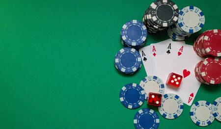 Cards, dice and poker chips on a green table, with copy space. Casino concept