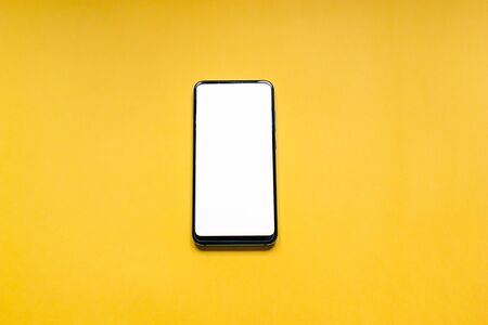 smartphone with white screen in vertical position isolated on a yellow background. Technology...