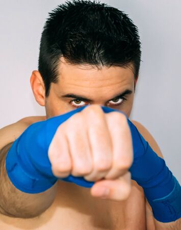 boxer with an intense look, blue bandages. Unfocused fist. Sporting conceptの写真素材