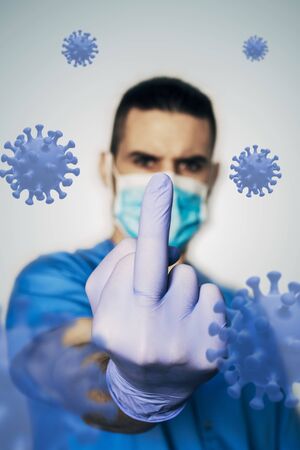Masked nurse takes the middle finger off the coronavirus. Concept covid-19の写真素材