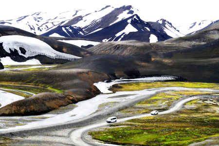Tourist vehicles driving in the valley of volcanic mountains Landmannalaugar in summer time in Icelandの写真素材