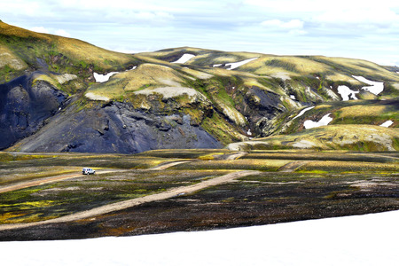 Tourist vehicle driving in the valley of volcanic mountains Landmannalaugar in summer time in Icelandの写真素材