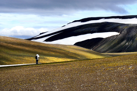 A photographer standing in front of beautiful volcanic mountains in the national park Landmannalaugar, Icelandの写真素材