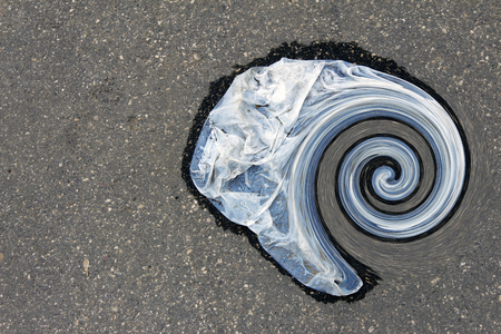 Wet plastic bag lying on the asphalt rolled into a spiralの写真素材