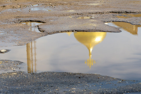 The yellow (gold) dome of the Church with the cross is reflected in a puddles of bad roadsの写真素材