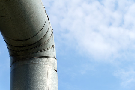 Curve old pipe (with stainless steel) on a background of blue sky with white clouds.の写真素材