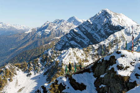The tops of the mountains covered with snow. The fall time of the year. The slopes are thickets of yellow and green trees. A man and a woman coming the stairs.の写真素材