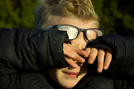 portrait of sad boy with hand on his eyesの写真素材