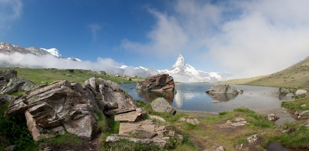Matterhorn mountain with morning clouds reflecting in Moosjisee, Alps, Switzerlandの写真素材