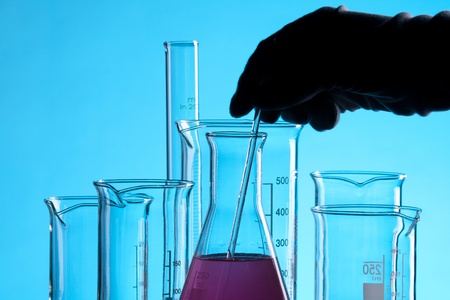 Laboratory technician working with laboratory glassware - chemical flasks with one colored solution.の写真素材