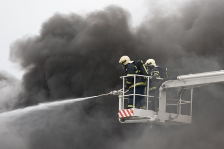 Two firefighters on ramp and smoke in backgroundの写真素材
