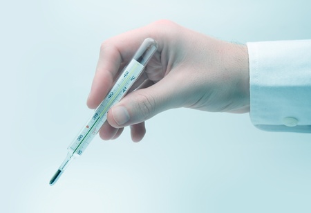 Medical concept - mercury thermometer hold in right hand - blue tintの写真素材