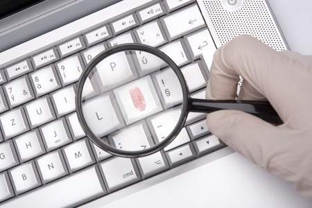 Laptop keyboard with fingerprint enlarged by magnifying glass - computer criminality conceptの写真素材