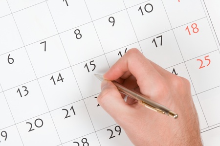 Hand with pen take a note into calendarの写真素材