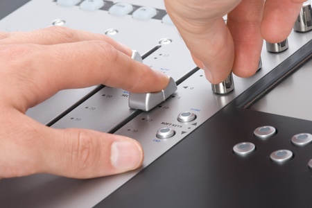 Sound engineer with hands on fader and knobの写真素材
