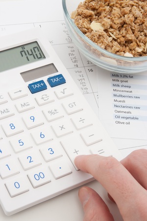 Healthy eating concept - man calculate his daily nutrition intake  Muesli in glass bowl, calculator, calendar and nutrition chart の写真素材