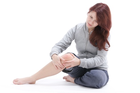 Woman palpate her painful knee  Studio shot against white background の写真素材