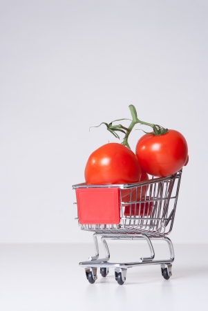 Buy fruit and vegetable concept  could be used for genetically modified food, GM food   Shopping cart  shopping trolley  with big tomatoes の写真素材