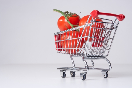 Buy fruit and vegetable concept  could be used for genetically modified food, GM food   Shopping cart  shopping trolley  with big tomatoes  の写真素材