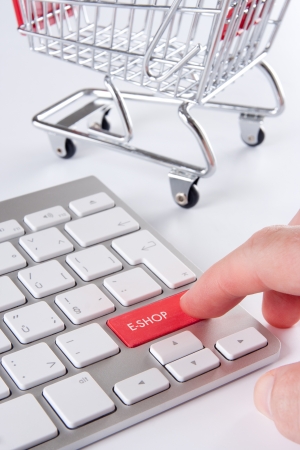E-shop (e-commerce) concept - keyboard with e-shop text and shopping cart (shopping trolley) in background.の写真素材