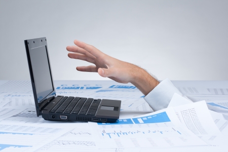 Drowning in paperwork concept  White collar worker reaching out after computer - rescue of paperwork の写真素材