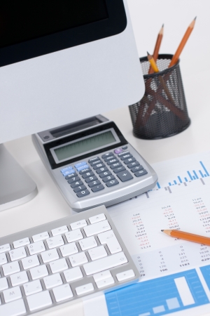 Concept of business analyst workplace - pencil, sheet with numbers, graph, keyboard, computer and calculator
の写真素材
