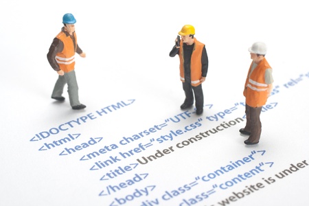 Printed HTML code of website  internet page  under construction  Construction worker figurines working on code の写真素材